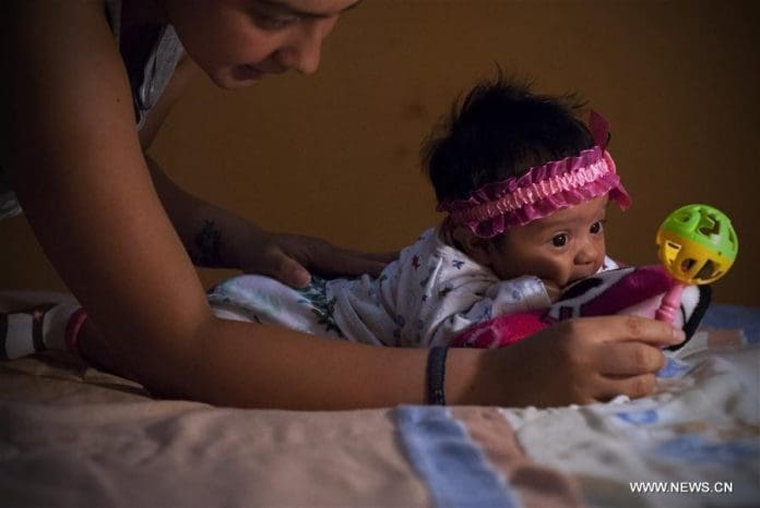 Image taken on Feb. 27, 2016 shows Angela Martinez, playing with her daughter Dominic Andrade (R), who suffers microcephaly, in Quito, capital of Ecuador. Dominic Andrade, 4 months old, permanently receives therapy at home and on the facilities of a hospital due to microcephaly that has affected her since birth. Since the World Health Organization (WHO) issued a global alert against the virus, on Feb. 1, the authorities of several countries in America have strengthened the dissemination of messages in mass media for people to avoid the bite of "Aedes aegypti" transmitter of Zika virus, dengue and chikungunya. However Zika virus continues to spread explosively in America, where there has been an increasing number of cases of microcephaly. (Xinhua file photo/Santiago Armas)