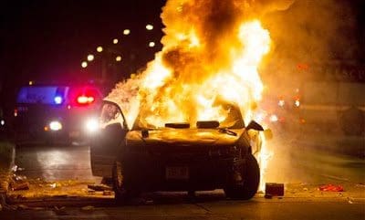 Milwaukee cop car burning A car burns as a crowd of more than 100 people gathers following the fatal shooting of a man in Milwaukee, Saturday, Aug. 13, 2016. The Milwaukee Journal Sentinel reported that officers got in their cars to leave at one point, and some in the crowd started smashing a squad car's window, and another vehicle, pictured, was set on fire. The gathering occurred in the neighborhood where a Milwaukee officer shot and killed a man police say was armed hours earlier during a foot chase. (Calvin Mattheis/Milwaukee Journal-Sentinel via AP)