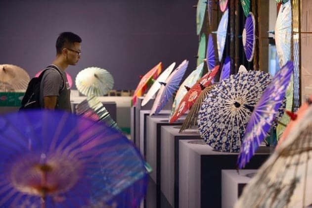 A visitor views silk umbrellas during a West Lake silk umbrella show in Hangzhou, capital of East China's Zhejiang Province, August 26. (Xinhua)