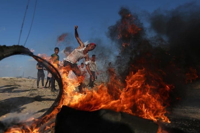 A Palestinian protester uses a slingshot to hurl stones at Israeli troops during clashes with Israeli troops on the Gaza-Israel border, east of southern Gaza Strip city of Khan Younis, Aug. 30, 2019. At least 54 Palestinians were injured on Friday, during clashes with Israeli soldiers in eastern Gaza Strip, close to the border with Israel, medics said. (Xinhua/Stringer)