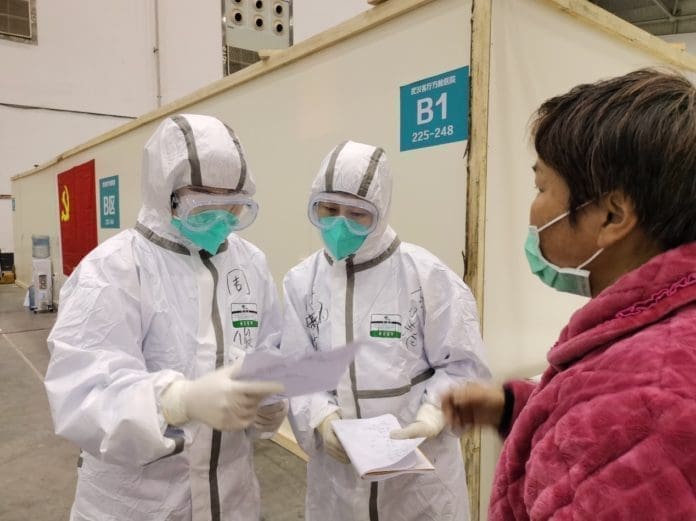 Medical staff record information of a patient at “fangcang” hospital in a cultural building complex dubbed “Wuhan Livingroom”, Feb. 9. (Photo by Li Han, People’s Daily)