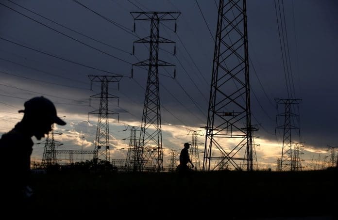 FILE PHOTO: Men walk past electricity pylons as they return from work in Orlando, Soweto township, South Africa March 18, 2019. REUTERS/Siphiwe Sibeko/File Photo