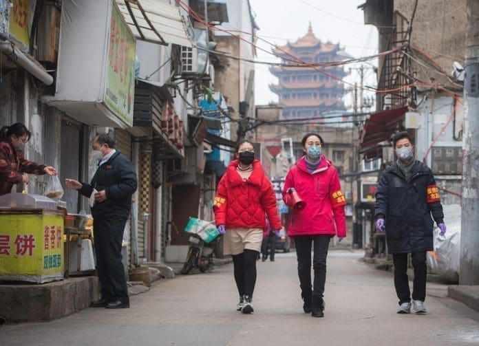 Community workers and volunteers use a speaker to publicize the information about prevention and control of the novel coronavirus at a street near the Yellow Crane Pavilion in Wuhan, central China's Hubei Province, Feb. 7, 2020. (Xinhua/Xiao Yijiu)