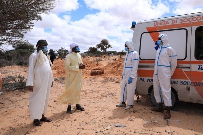 Family members of a person that died of COVID-19 converse with health workers during a burial ceremony, on the outskirts of Mogadishu, Somalia, May 8, 2020. Somali health ministry on Sunday confirmed 57 new cases of the novel coronavirus, bringing the total infections to 1,054. Fawziya Abikar, health minister said three people succumbed to the deadly respiratory disease, raising the death toll to 51. (Xinhua/Hassan Bashi)