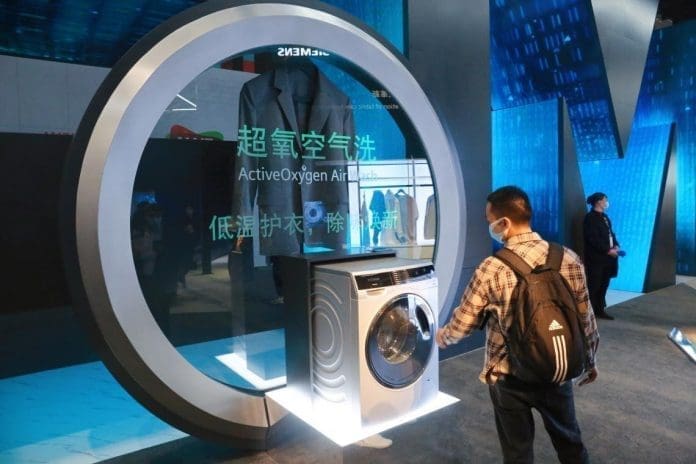A visitor watches an intelligent washing machine exhibited at the Appliance & Electronics World Expo 2021 held in east China’s Shanghai, March 23, 2021. (Photo by Chen Yuyu/People’s Daily Online)