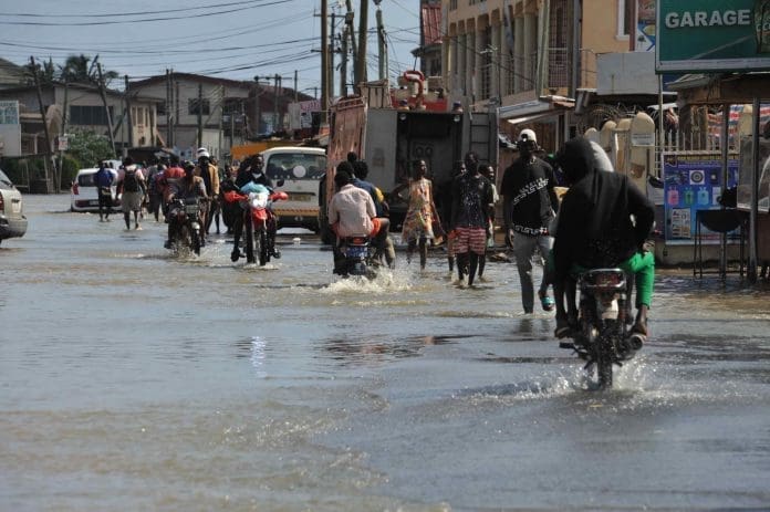 People wade through a flooded street in Accra, Ghana, on Oct. 5, 2022. Thousands of residents of the southwestern part of Accra, the Ghanaian capital, have been displaced due to the spillage of the Weija Dam. The spillage of the dam was caused by excess water following torrential rains over the weekend, which contributed to the water level behind the dam rising above the maximum level. The dam built on the Densu River is the source of potable water for more than half of the 5.4 million population of the national capital. (Photo by Seth/Xinhua)