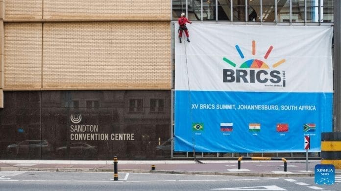A worker arranges a signboard of the 15th BRICS summit outside the Sandton Convention Center in Johannesburg, South Africa, Aug. 17, 2023. The 15th BRICS summit is to be held in Johannesburg, South Africa, on Aug. 22-24. (Xinhua/Zhang Yudong)