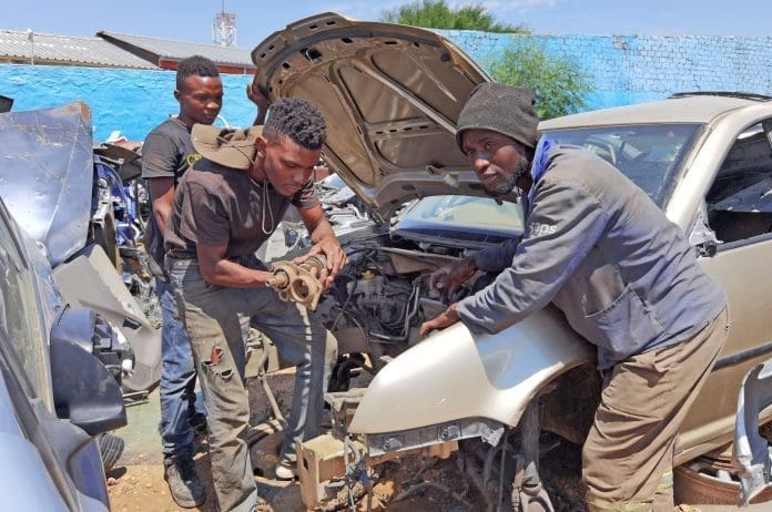 Workers strip a car at a scrap yard in Windhoek, Namibia, on Dec. 16, 2023. (Photo by Ndalimpinga Iita/Xinhua)